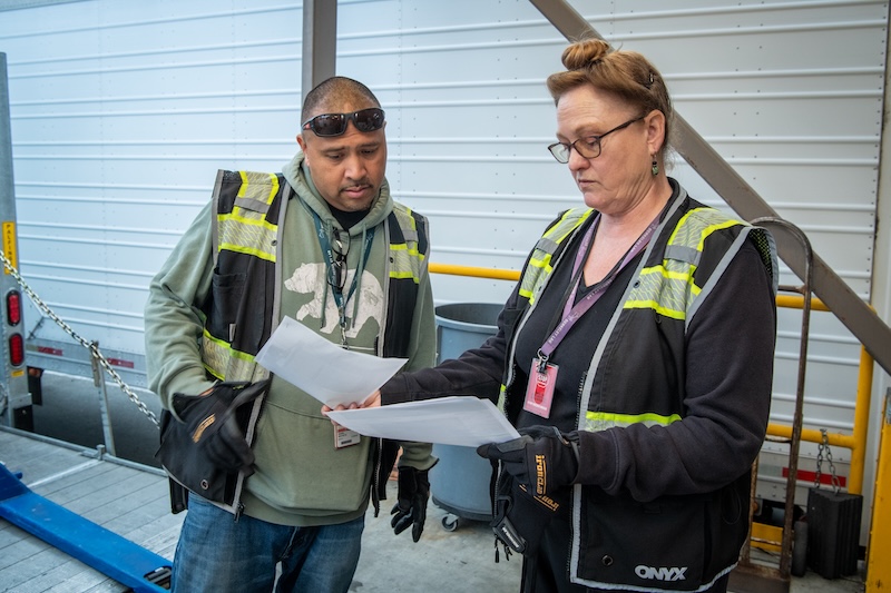 Lori Colton (right), Facilities Division Lead Truck Driver, and Daniel Ancheta, Truck Driver, discuss the morning’s shipments at Lawrence Berkeley National Laboratory’s Shipping & Receiving facility, 09/09/2025.